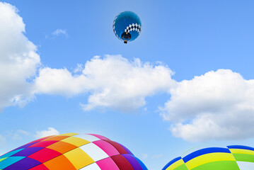 Colorful hot air balloon flying over blue sky with white clouds	