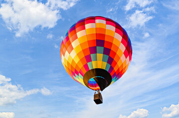 Obraz premium Colorful hot air balloon flying over blue sky with white clouds 