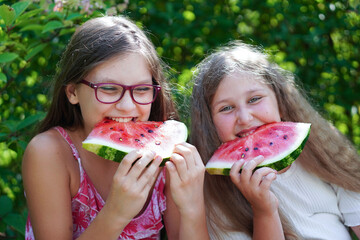 Close up portrait of two young girls laughing, eating  and enjoying a watermelon.