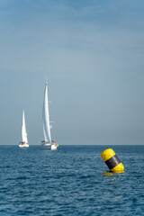 Yellow buoy and sailboats competition in the background