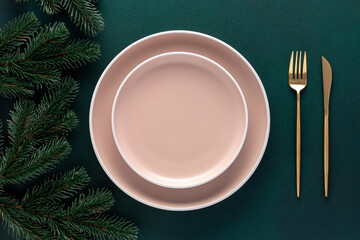 Empty beige plates on a dark green background. Top view. Card or menu template, flat design. Tableware, crockery. Aerial view, copy space. Christmas table setting with New Year decorations.