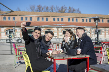 Group of cheerful young friends taking selfie portrait. Happy people having a coffee smiling. Concept of community, youth lifestyle and friendship 