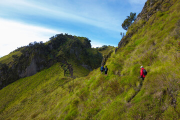 Some hikers walked on the foothpath at the cliff to get to the top of the mountain