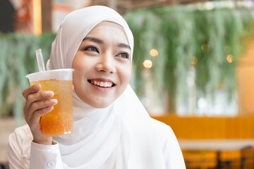 Happy Muslim woman drinking delicious halal boba tea aka bubble tea or pearl tea, looking up