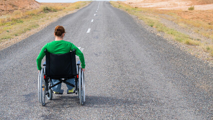 Woman in a wheelchair on a highway in the steppes. 