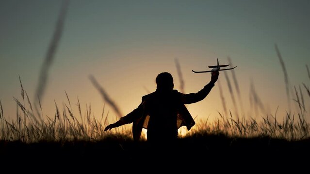 Happy girl with oy in natural park. Child runs on grass with an airplane. Chidhood dream. Happy baby girl with toy airplane at sunset. Child runs on grass in field. Dream travel concept