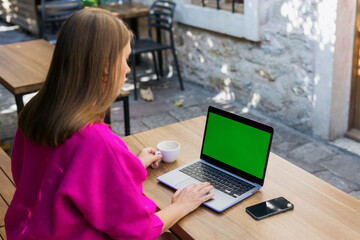 An unrecognisable young woman in a cafe. Laptop with chroma key . The concept of remote work