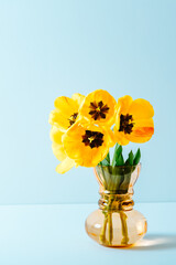 Big flowers bouquet of yellow tulips in vintage glass vase on blue background. Business card. Invitation postcard. Mockup design. International holiday. Banner. Hello spring. 8 march. Copy space