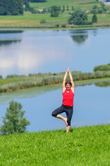 Junge Frau bei Pilates-Übungen in der Natur, Balance-Schulung und Muskelkräftigung