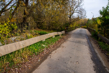 A concrete railing by a deserted and neglected road on a gloomy autumn day. Road.