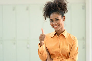 Image of beautiful African American woman showing thumbs up and looking confidently to camera