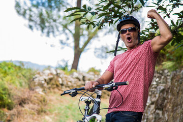 Naklejka premium funny mature man with bicycle on the mountain