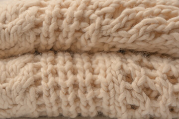 A fragment of beige knitted fabric, knitted from white sheep wool.