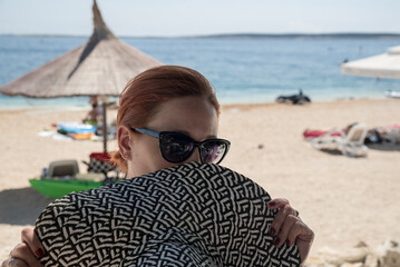 kobieta w okularach na plaży z kapeluszem