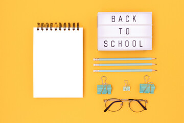 Back to school. Lightbox with letters and mint colored stationery on a yellow background. Clean notepad mockup.