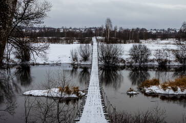 Winter walk. Suspension bridge connecting the two banks of the river.
