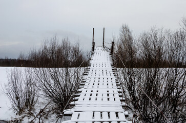 Suspension bridge in Russia in winter. Risky dangerous bridge for pedestrians 