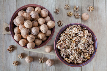 Walnuts and walnut kernels in plates on a wooden table