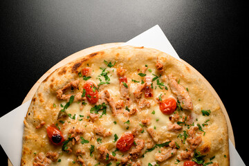 Part of top view on pizza with cherry tomatoes and chicken garnished by green