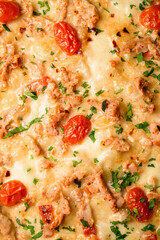 Close-up of pizza topping with cherry tomatoes and chicken garnished by green