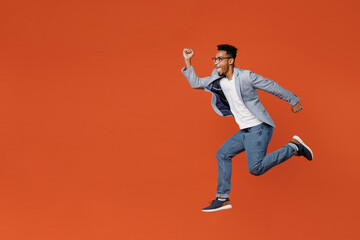 Fototapeta na wymiar Full body side profile view young employee business man corporate lawyer wear classic formal grey suit shirt glasses work in office jump high run fast isolated on plain red orange background studio.