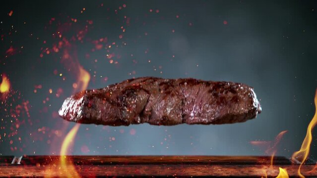 Flying pieces of grilled beef steak falling on table. Filmed on high speed cinema camera, 1000 fps.