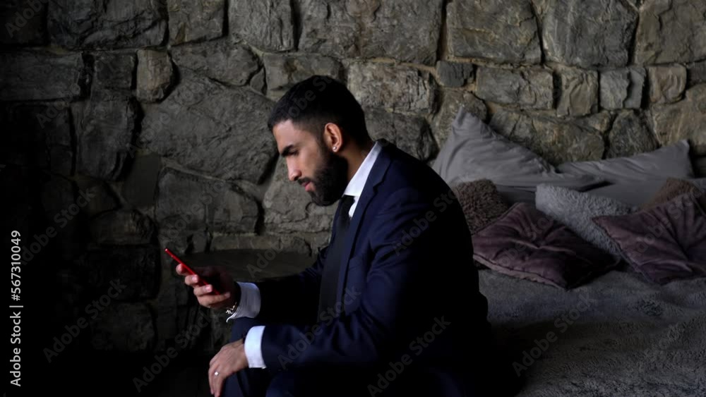 Poster middle eastern businessman recording audio message for sending voice sms during cellphone chatting w