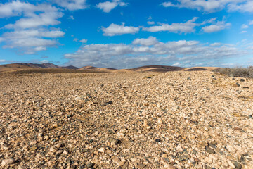 amazing desert landscape with blue sky and white clouds with mountain range in the background....