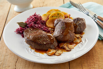 Plate with meat dish on wooden table