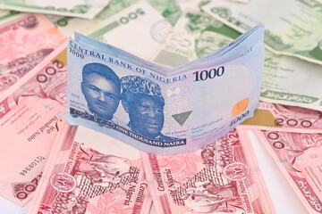 slightly bents 1000 new Nigerian Naira note on a pile of 500 and 200 naira banknotes, stack of one...