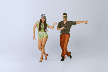 Positive vibes. Young beautiful girl and artistic man in bright retro clothes dancing disco...
