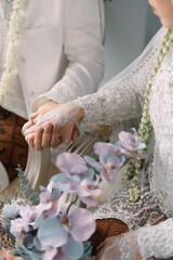 close up of bride holding hands in white traditional dress