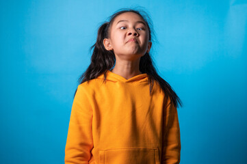 Fototapeta premium the studio isolated a portrait image of the acting of a happy girl with a blue backdrop.