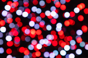 Red, white and gray bokeh light circles on a black background. Defocused colorful confetti backdrop