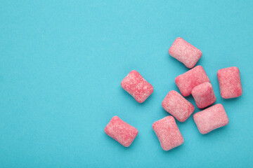 Chewing pink gum pieces on blue background. Space for text