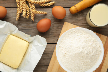 Ingredients for baking or cooking, egg flour, rolling pin butter, milk on a grey wooden background Cookie pie or cake recipe.