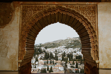 Arab arch that in the background you can see a town of white houses in the Andalusian style made in Granada
