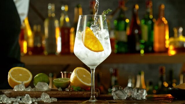 Super slow motion of preparing gin and tonic drinks with speed motion. Filmed on high speed cinema camera, 1000 fps, placed on high speed cine bot. Bar with bottles on background.