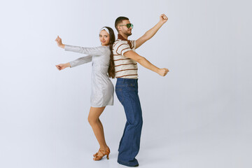 Having fun. Young beautiful girl in silver dress and stylish man dancing disco dance isolated over...