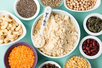 Healthy Dry Pea Protein Powder and Plant Based Protein Food (legumes, lentils, beans, seeds) on Blue Green Background.