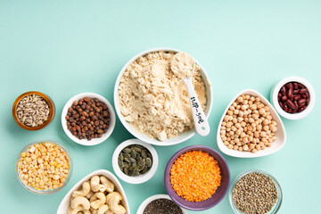 Healthy Dry Pea Protein Powder and Plant Based Protein Food (legumes, lentils, beans, seeds) on Blue Green Background.