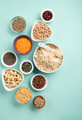 Healthy Dry Pea Protein Powder and Plant Based Protein Food (legumes, lentils, beans, seeds) on Blue Green Background.