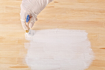 white paint with a brush painting a wooden background with texture