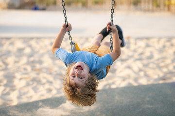 Swinging on playground. Happy child enjoy swinging. Kid swinging. Happy little child having fun on...