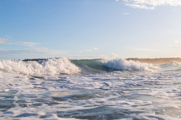 Obraz premium Broken white wash under the sunset light at beach shore.