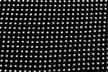 Black cotton folded fabric with dotted metal rivets as background