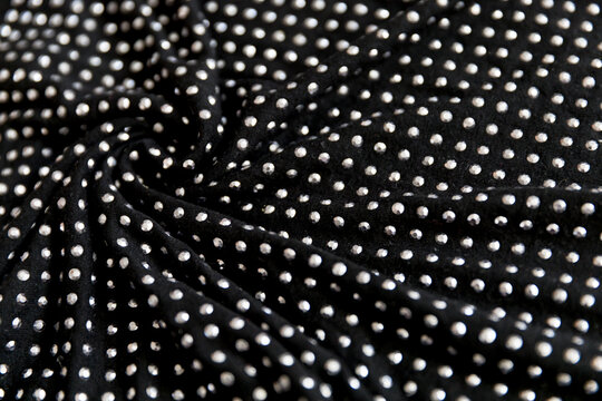 Black cotton folded fabric with dotted metal rivets as background
