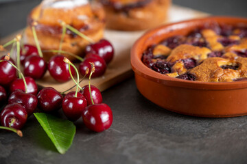 Red fresh cherries on a dark table with baking from it in an earthenware dish