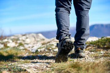 Legs of a hiker in trekking boots walking in the mountains closeup shot. Feet of walking tourist...
