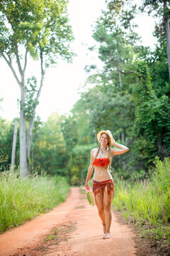 A young woman smiles while walking down a dirt road.
